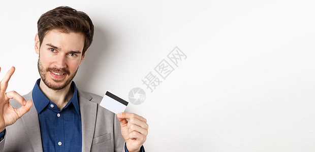 购物 帅哥展示好的标志和塑料信用卡 一切尽在掌握 不用担心的手势 白色背景促销企业家情绪胡须广告套装男人生活工作人士图片