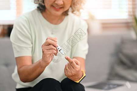 糖尿病和老年保健概念 用拔刀笔进行血液采样的糖尿病成年女士的裁剪镜头图片