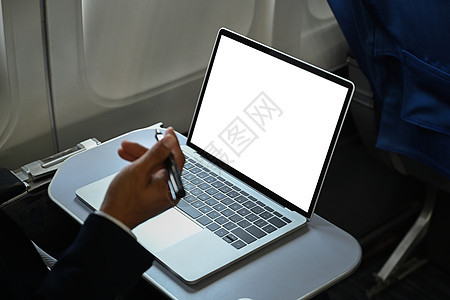 商业商坐在飞机机舱时使用笔记本电脑对商务人士进行剪切的观察 用于广告设计的空白屏幕图片