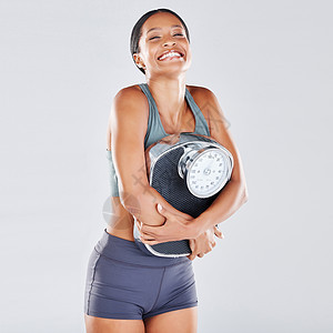在灰色背景下与一名黑人女运动员在演播室进行饮食 减肥和体重秤 以获得身体积极性或健康 健身 体重秤和减肥与一位年轻女性为健康摆姿图片