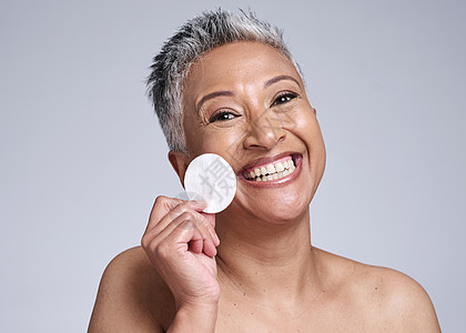 快乐的高级女性 面部皮肤病学中用于护肤和清洁面部的肖像棉 用垫子卸妆 灰色背景的工作室里的老妇人和水疗模型的自然卫生图片
