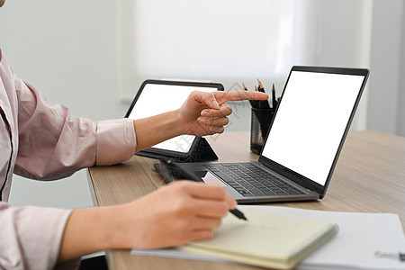 商业妇女用笔记本电脑屏幕和笔记本写字的刻画图像图片