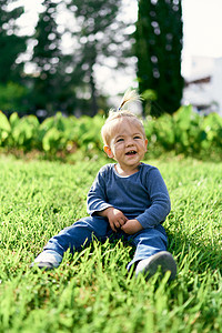 带着马尾辫的笑笑孩子坐在绿草坪上图片