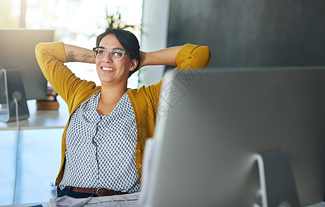 那种飞向成功的感觉……一位年轻的女商务人士在现代办公室的办公桌前放松图片