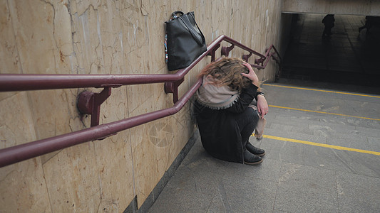 一个女孩在地铁的楼梯边哭泣图片