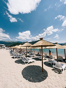 在海边的沙滩上 躺椅上的稻草沙滩伞站立图片