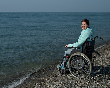 在海边坐轮椅的 土化的caucasians女人事故麻痹海浪快乐海洋椅子保健疾病女性残障图片