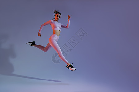 坚定的体育女运动员在中空中锻炼时因工作室背景而进行心操锻炼身体成人赛跑者运动装跑步爆炸慢跑者训练运动健身房图片