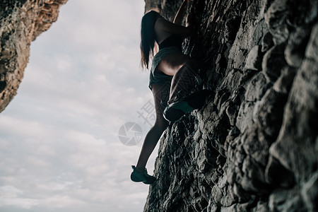 攀登岩石的体育妇女 身材苗条的年轻女子在火山玄武岩洞穴中攀爬 欣赏美丽的海景 女运动员在大自然中训练 女人克服困难的攀登路线攀岩图片