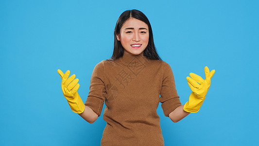 带有防护手套的神经紧张的亚洲房客 与清洁房屋有问题图片
