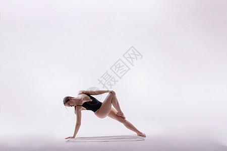 穿黑体装的年轻瘦弱女性 在白色工作室墙壁背景上做瑜伽伸展练习健康概念运动连体衣可用胸衣体操体育舞蹈家健身房图片