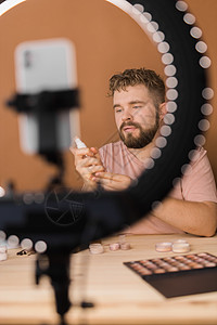 男人在视频博客上谈论化妆和美容产品 拍摄化妆教程的男性 Guy 教授使用她的手机制作教程  多样性和博主概念影响者容貌商业社交彩图片
