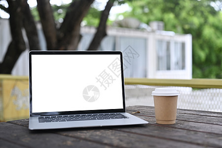 在户外的木制桌上装上电脑笔记本电脑和咖啡杯图片