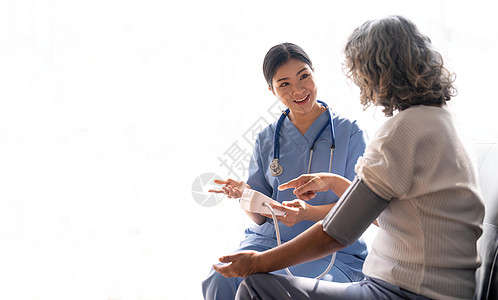 快乐的老年妇女在疗养院由护理人员测量血压 测量一位资深妇女的血压的愉快的护士保健医生诊所疾病医学女性成人微笑帮助医院图片