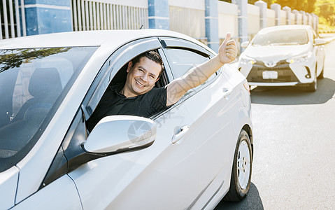 微笑的司机在路上竖起大拇指 满意的司机竖起大拇指 安全驾驶理念 车里的年轻司机竖起大拇指图片