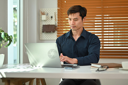 英俊的商务人士使用便携式计算机在家庭办公室工作 远程工作 技术和生活方式概念图片