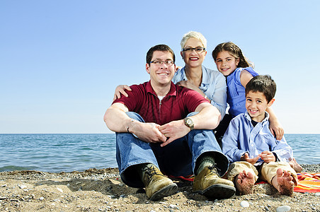 幸福的一家人坐在沙滩上图片