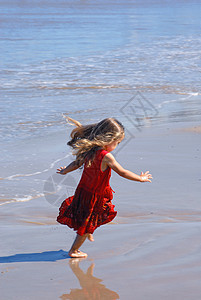 快乐的女孩在海滩上玩 水 海洋 裙子 红色的图片