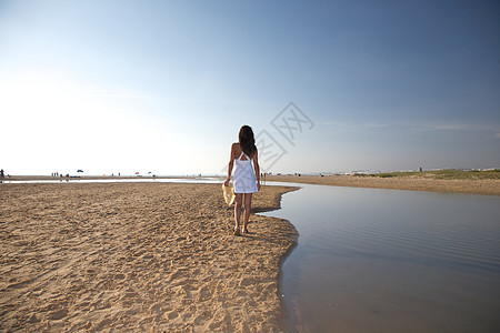 在海滩上走在河边的女人图片