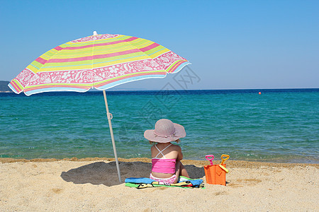 小女孩坐在沙滩上遮着阳光图片
