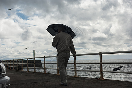 海滨带雨伞的老人男子图片