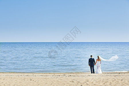 幸福的结婚情侣站在海滩上图片