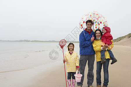 在海滩上快乐的一家人 带着雨伞在沙滩上 冒充图片