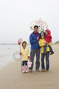在海滩上快乐的一家人 带着雨伞在沙滩上 桶图片