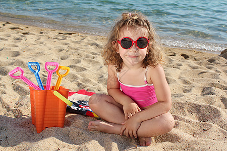 有太阳眼镜的小女孩 坐在沙滩上图片
