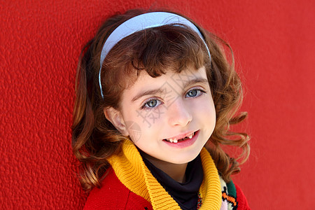 微笑的小女孩 缩着前牙 在红色上微笑 卷曲图片