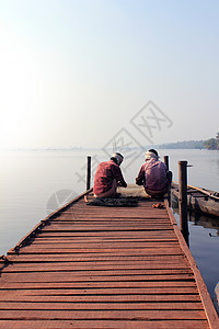 在克拉拉的Cherai与渔获鱼坐在一起的渔民图片