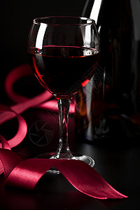 玻璃红葡萄酒和黑色背景的红丝带 瓶子 禧年 干杯图片