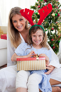 微笑的母亲和女儿拆开圣诞礼物时的笑容图片