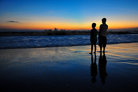 海洋日落时两个男孩的休眠图片