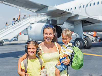 年轻母亲和两个孩子在飞机前图片