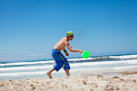 夏天在海滩上玩游骑球的有魅力的男人 娱乐 天空高清图片