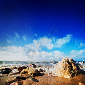 海浪在阳光明媚的沙滩上撞击岩石图片
