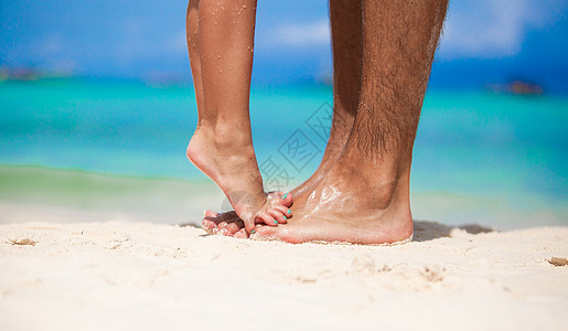 小女孩站在她父亲的脚上 在白沙滩上 美丽的 天图片