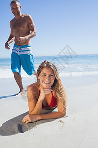 微笑的女人躺在沙滩上 而男人与她同在图片