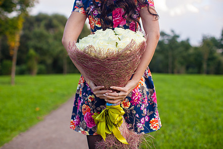 一个穿有色裙子的年轻女孩手上 盛着白色玫瑰花朵 美得难以置信图片