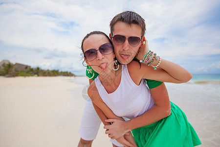 年轻美丽和快乐的情侣 在白色海滩的相机上展示舌头图片