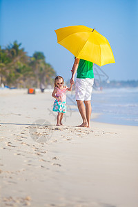 年轻父亲和他女儿在黄色雨伞下行走的后视镜图片
