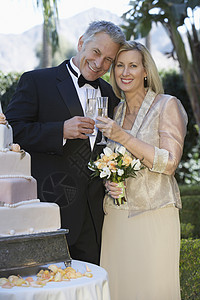 幸福的情侣在婚礼蛋糕附近 烤香槟小笛子的肖像图片