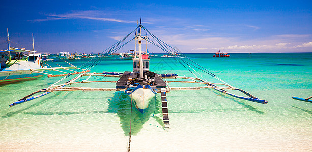 菲律宾博拉凯白海滩上有绿绿水的白滩船图片