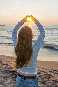 女孩在海滩上握着双手的心型 手指 女士 美丽图片