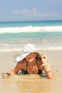 海滩上拿着帽子的年轻女子 享受暑假图片