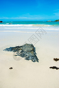 在沙滩上摇着蓝天的岩石图片