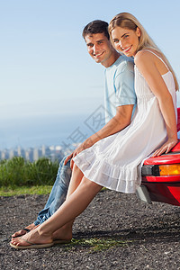 快乐的一对情侣坐在他们的出租车车兜帽车上图片