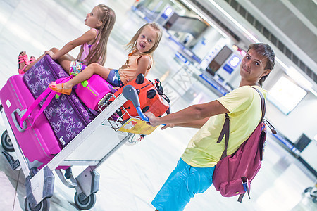 年幼的父亲和在机场携带行李的可爱小女儿 旅行图片