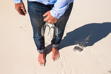 在白沙滩上赤脚走路的男子手握着两个杯子 紧闭两杯眼镜图片